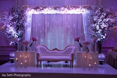 a chair and table with flowers on it in front of a purple lit up stage