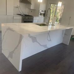 a kitchen with an island in the middle of it and white cabinets on both sides