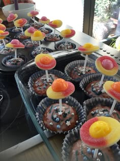 cupcakes with candy toppings on sticks in trays next to stove top