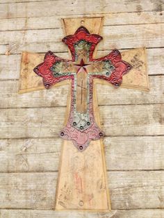 an old wooden cross with red and green designs on the front is hanging on a wall