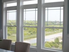 a dining room table and chairs with three large windows