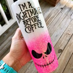 a hand holding up a pink and white coffee cup with a skull painted on it