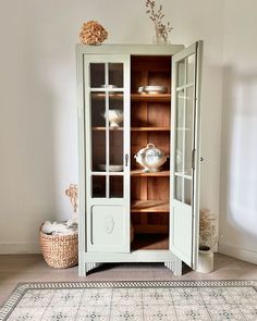 an old china cabinet with glass doors in the corner, and a rug on the floor next to it