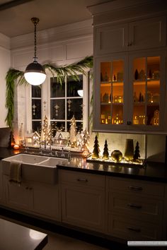 a kitchen decorated for christmas with candles and lights on the windowsill, along with other holiday decorations