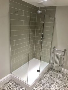 a walk in shower sitting next to a white radiator on a tiled floor