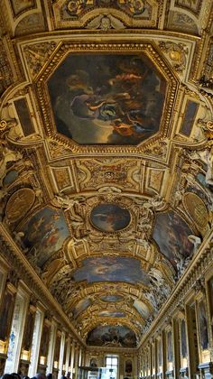 an ornate ceiling with paintings on it and people walking in the hallway between two walls