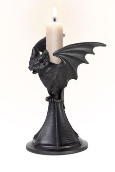 a candle holder with a black dragon figurine on it and a lit candle