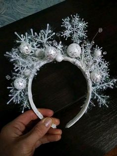 a hand holding a white headband with snowflakes and balls on the top