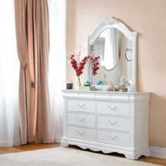 a white dresser sitting in front of a window with a mirror on top of it