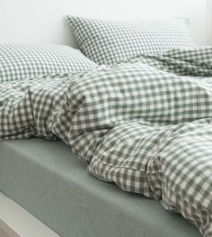 an unmade bed with checkered sheets and pillows