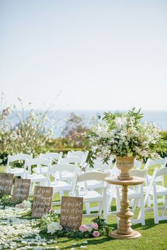 an outdoor ceremony set up with white chairs and flowers