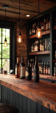 a bar with several bottles on it and lights hanging from the ceiling above them, in front of a window