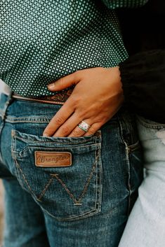 two people standing next to each other with their hands in the back pocket of their jeans