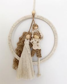 two dolls are hanging on a white circular ornament