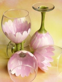 three wine glasses with pink flowers in them on a yellow and pink background, one is filled with water