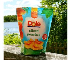 a bag of diced peaches sitting on top of a wooden table next to water