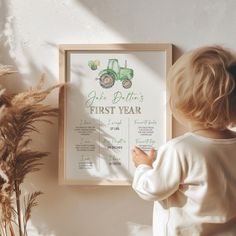 a little boy standing next to a poster with a tractor on it's back