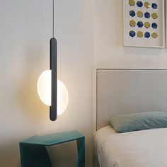 a white bed sitting next to a wall mounted light