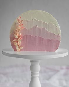 a cake with pink and white frosting sitting on top of a white cake plate