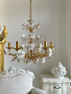 a chandelier hanging from the ceiling in a room with white walls and furniture