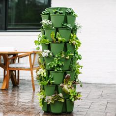 a tall stack of green plastic containers with plants growing out of them on a patio