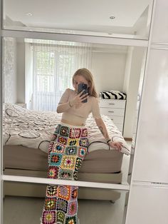 a woman taking a selfie in front of a mirror wearing a colorful crocheted skirt