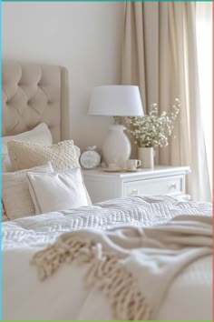 a white bed sitting next to a window in a room with curtains on the windowsill