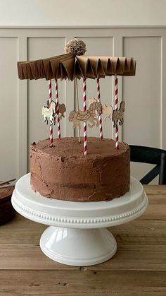 a chocolate cake on a white pedestal with two red and white candy sticks sticking out of it