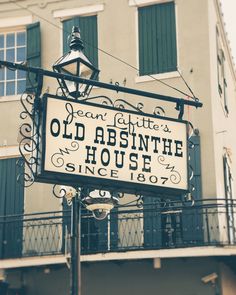 an old absinthe house sign hanging from the side of a building with green shutters