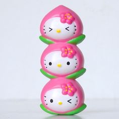 three hello kitty eggs stacked on top of each other with pink bows and green stems