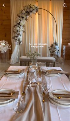 the table is set with white flowers and place settings