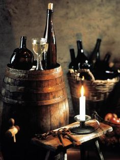 a candle is lit in front of some wine bottles and other items on a table