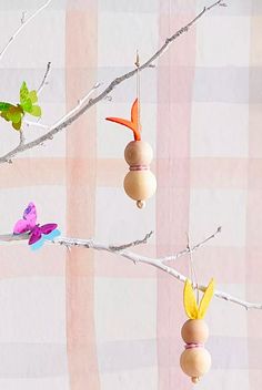 three wooden beads hanging from a tree branch with butterflies on it and pink checkered background