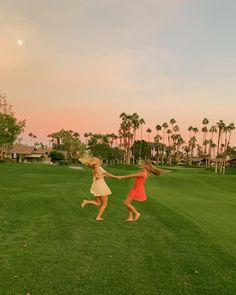 two girls are playing in the grass with their arms around each other and holding hands