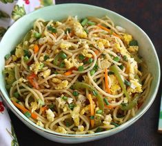 a bowl filled with noodles and vegetables on top of a table next to a napkin