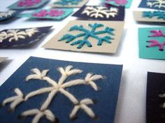 many different colored snowflakes are arranged on a white table top with blue and pink squares