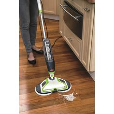 a woman is cleaning the floor with a green and white mop in her kitchen