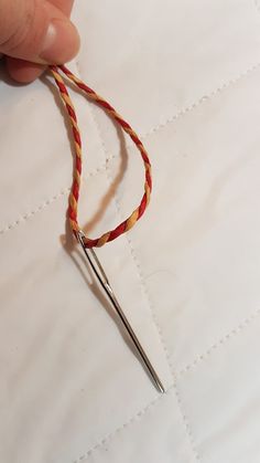 a pair of scissors is being used to thread a piece of fabric with red and yellow yarn