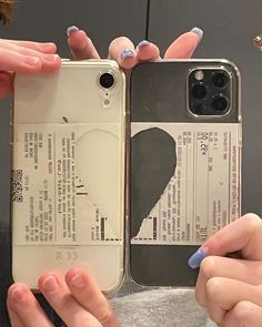 two women holding up their cell phones in front of them, one with her fingernails