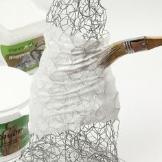 a white sculpture with a brush sticking out of it's top and some other items in the background