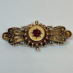 Beautiful Etruscan Revival brooch created in 14K yellow gold accented with a brilliant garnet. The brooch has an unreadable mark. Please message us if you have questions. Metal Type: 14K Yellow Gold Hallmarks: unreadable  Metal Finish: Textured Item Weight: 7.5 grams Measurements: Length 21.6mm by  Width 48mm (approximately) Condition: good condition  Visit our eBay store "Donna's Jewelry Room" for more great vintage jewelry. Thank you for shopping with us! Ornate Yellow Gold Brooch For Ceremonial Use, Ornate Yellow Gold Brooches For Ceremonial Use, Ornate Yellow Gold Brooches For Ceremonial Occasions, Ornate Yellow Gold Brooch For Formal Occasions, Yellow Gold Baroque Brooch For Formal Occasions, Ornate Red Jewelry Brooch, Victorian 14k Gold Brooches For Formal Occasions, Victorian 14k Gold Brooch For Formal Wear, Formal Yellow Gold Baroque Brooches