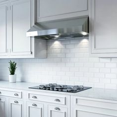 a kitchen with white cabinets and stainless steel stove top hood over the range in front of an oven