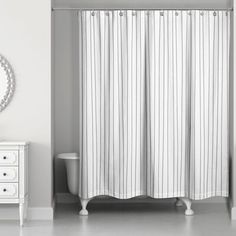 a black and white photo of a bathroom with a shower curtain, toilet and dresser