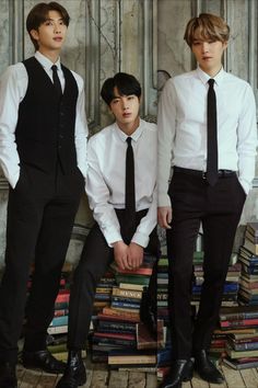 three young men in suits and ties standing next to each other with books on the floor