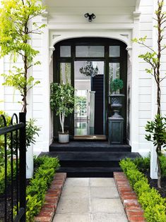 a black and white front door with potted plants