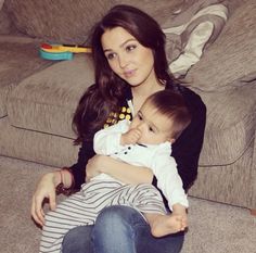 a woman sitting on the floor holding a baby