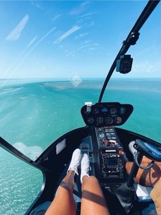 the view from inside an airplane looking down at the water and sky, with someone's feet in the cockpit