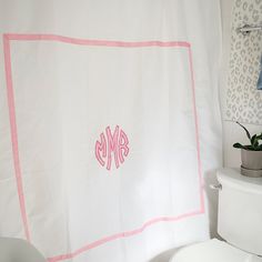 a monogrammed shower curtain in a bathroom with pink trim on the border and white toilet