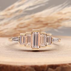 a three stone diamond ring sitting on top of a piece of wood