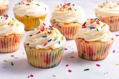 several cupcakes with white frosting and sprinkles